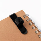 Black pen holder  on a brown notebook with a white background