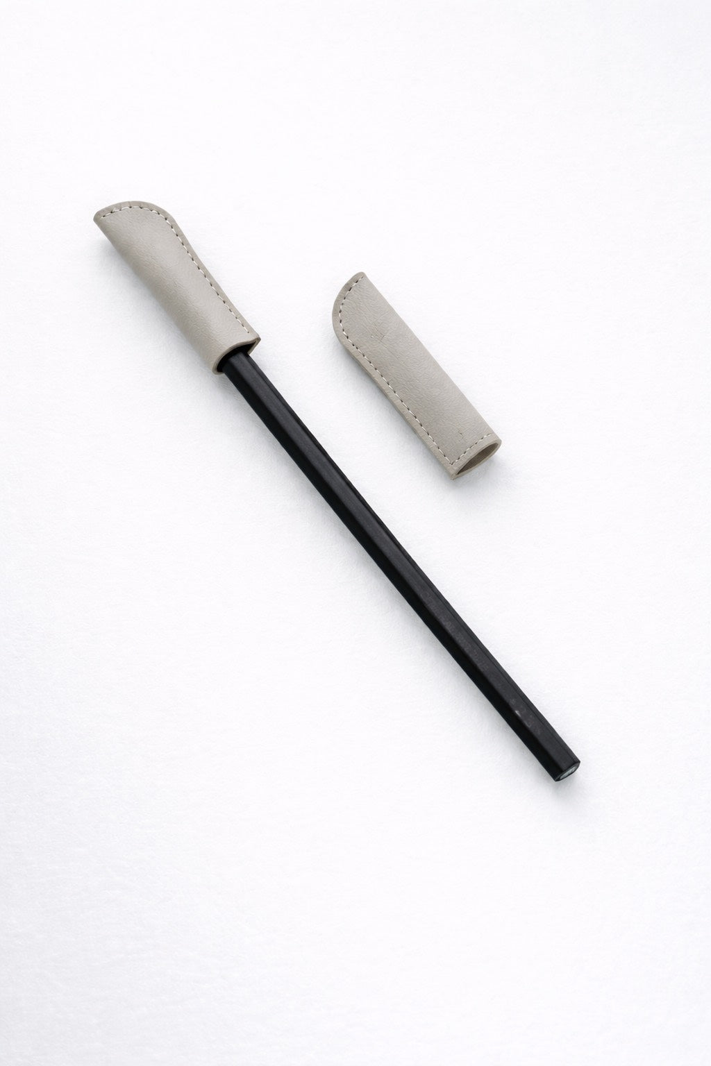 Black pencil with a 2 gray leather cap on a white background