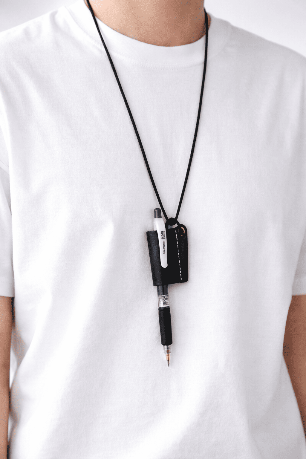 Person wearing a white shirt with a black pen holder strap on a white background